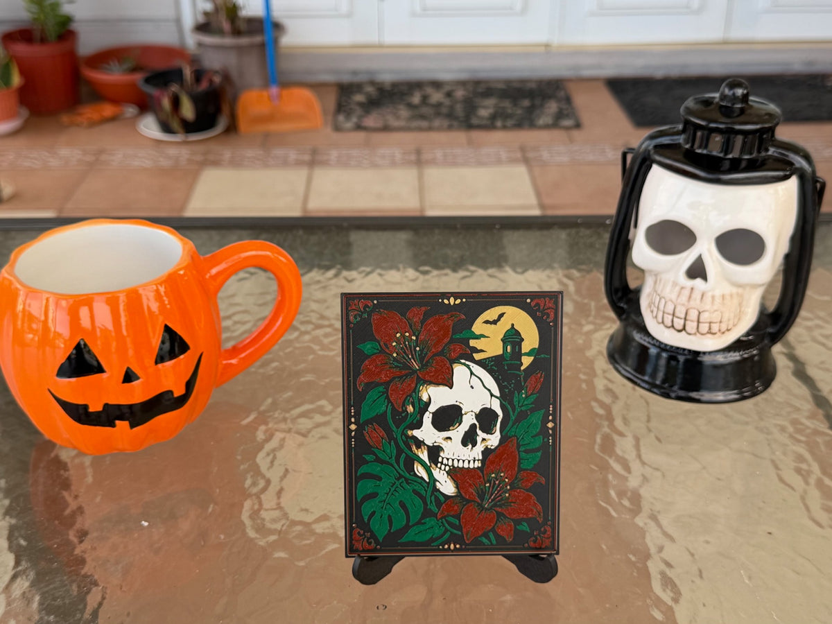 Calavera Tropical Halloween art print on a display stand; pumpkin mug and skull lantern are photo props