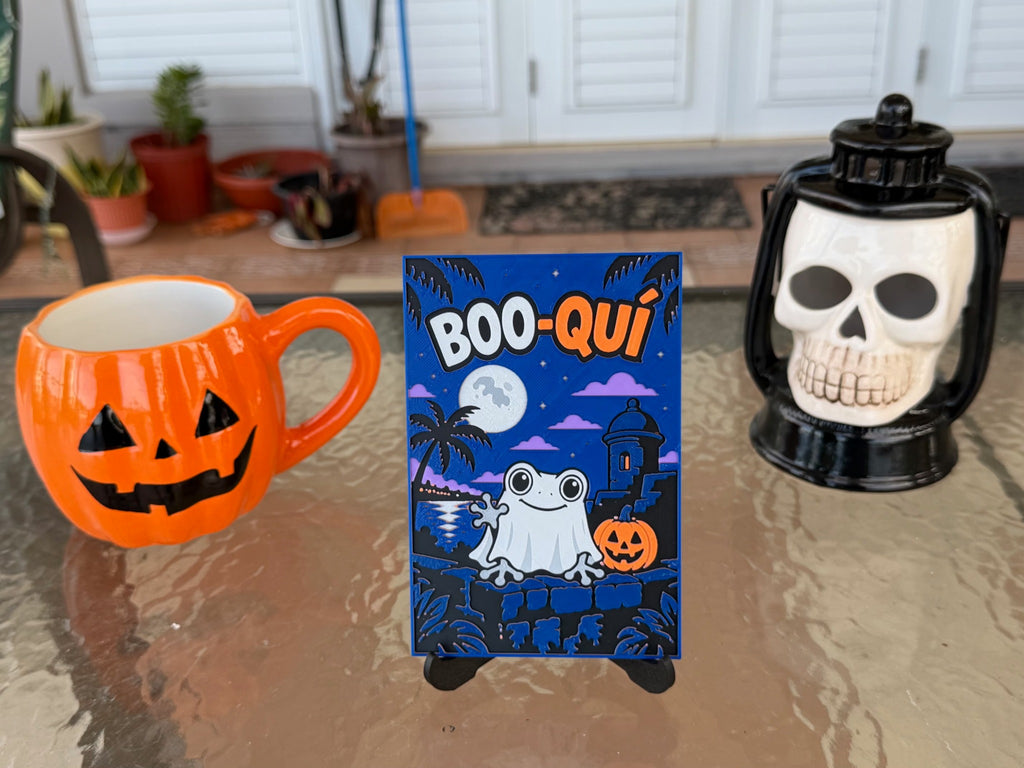BOO-QUÍ Halloween art print on a display stand; pumpkin mug and skull lantern are photo props